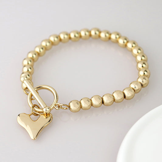 Golden bead and heart charm t-bar bracelet